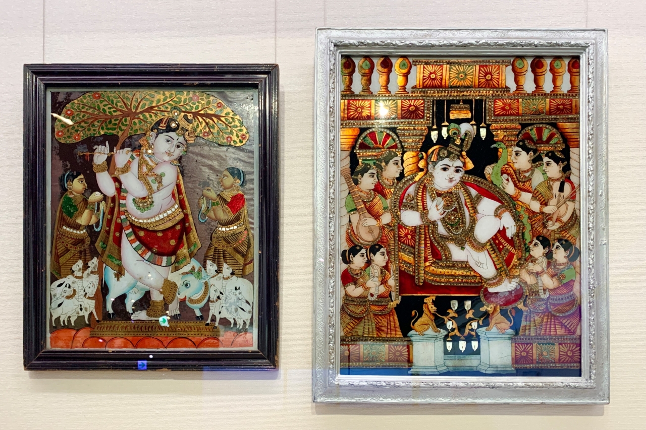 用金箔和銅片裝飾華麗的玻璃畫作。 ■（左圖）未知的“牧羊人吹笛（克里希納）”，（右圖）未知的“被女性音樂家包圍的克里希納” 南印度/19世紀末-20世紀初/福岡亞洲美術館（黑田）豐收藏）